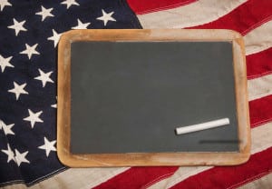 Small chalkboard with a piece of chalk sitting on an American flag