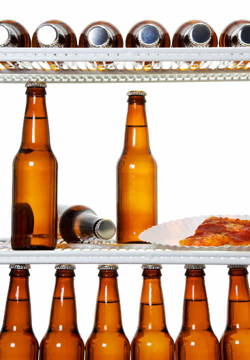 Stock image of interior of a refrigerator full of beers and a slice of pizza