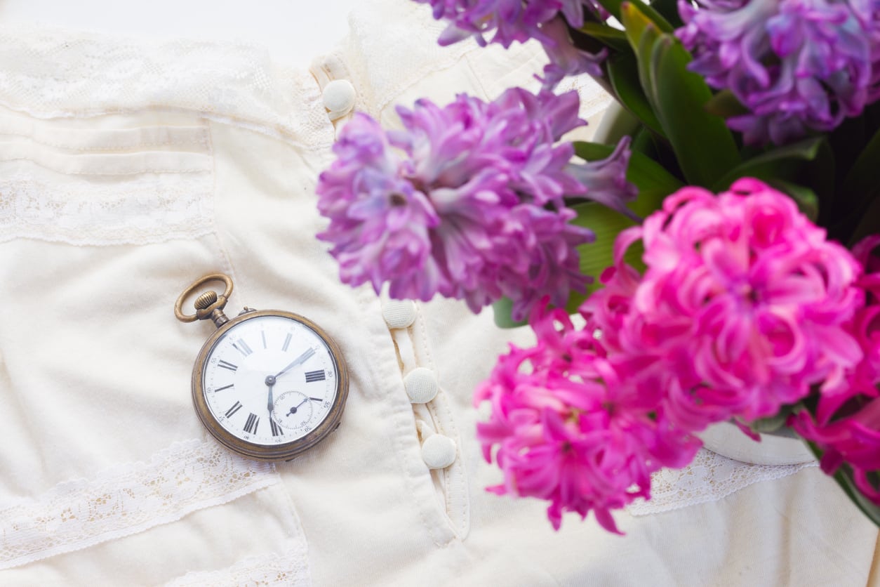 Pink and violet hyacinth flowers with retro dress and antique pocket watch