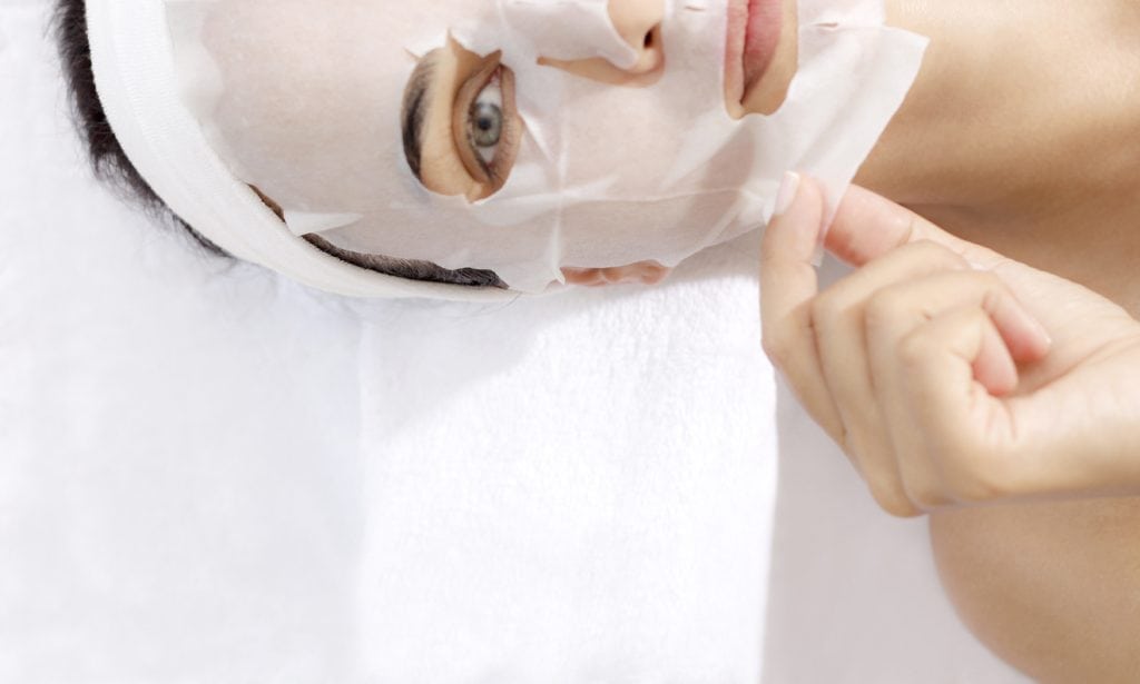 Caucasian female is taking off facial mask.