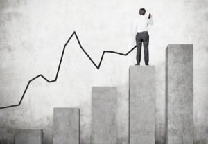 businessman drawing arrow on wall standing on chart