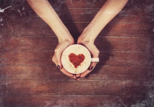 woman holding hot cup of coffee, with heart shape