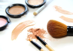 Broken powder, foundation and brushes on the white background